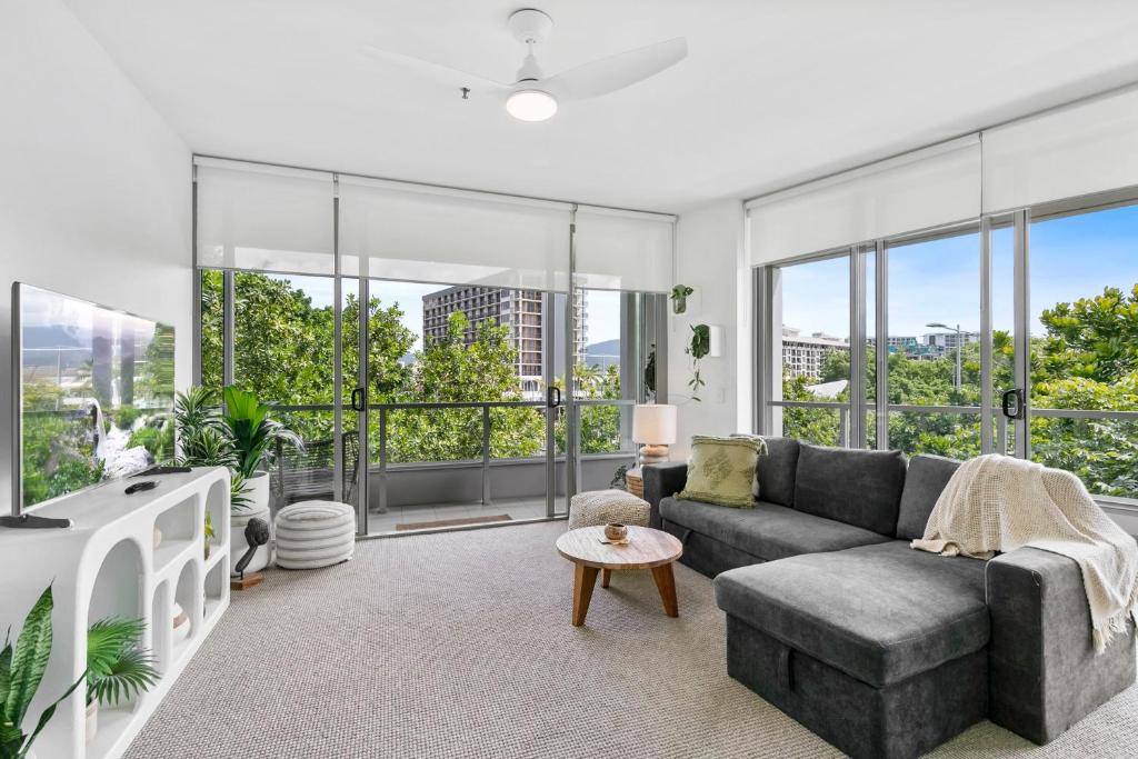 sala de estar con sofá gris y ventanas grandes en Coastal Harbour Lights I Pool, Gym & prime Location, en Cairns