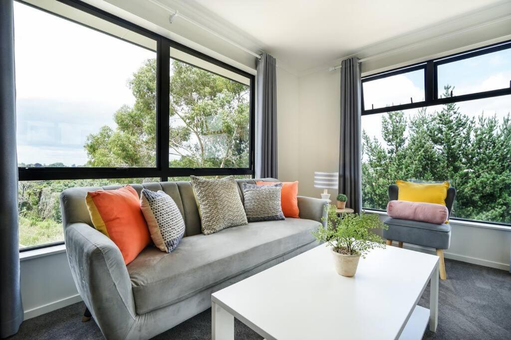 a living room with a couch and large windows at Riverview Retreat-4 bedrooms Brand New House In Hamilton in Hamilton