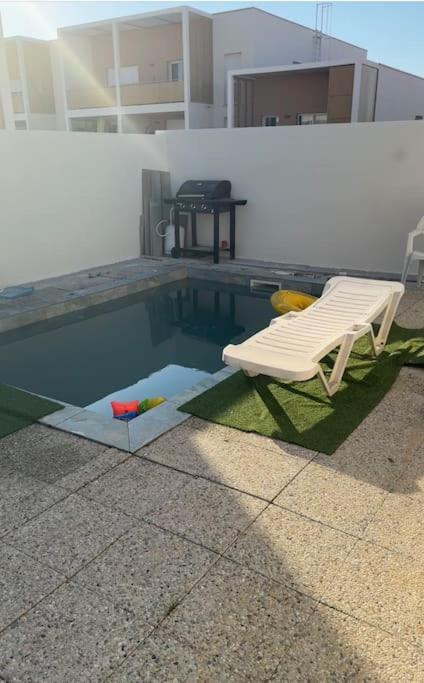 une chaise blanche assise à côté d'une piscine dans l'établissement Maisons 3 chambres avec piscine, à Nissan-lez-Enserune