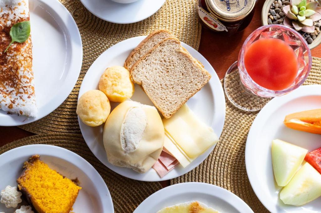 une table recouverte de assiettes de nourriture avec des sandwichs et des fruits dans l'établissement Pousada Portal da Atalaia, à Fernando de Noronha