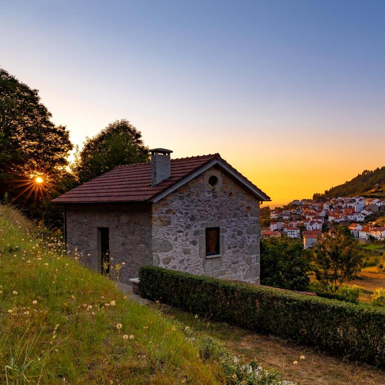 a small stone house on a hill at sunset at Casas do Gato in Valezim