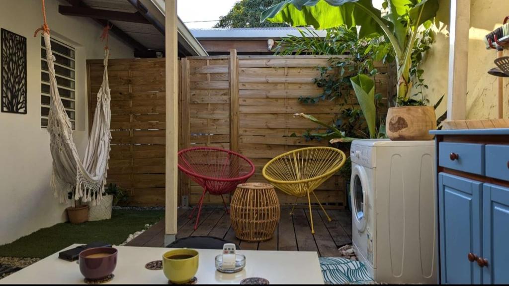 eine Terrasse mit 2 Stühlen und einer Waschmaschine in der Unterkunft Le Patio Fleuri - Studio et terrasse privé à Cayenne in Cayenne
