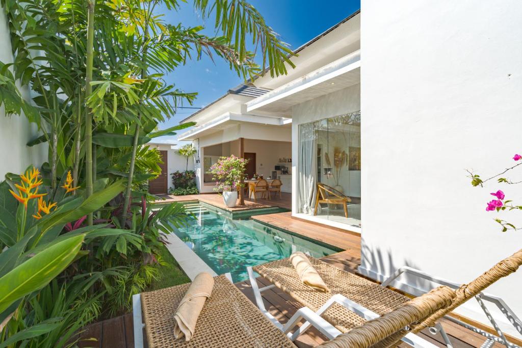 an outdoor swimming pool with chairs and a villa at Villa Lior - 1BR Luxury Hideaway near Nyanyi Beach in Canggu