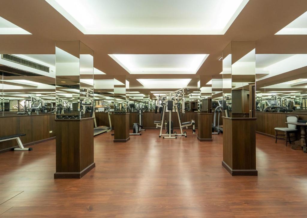 A large mirrored fitness room with cardio and strength-training equipment.