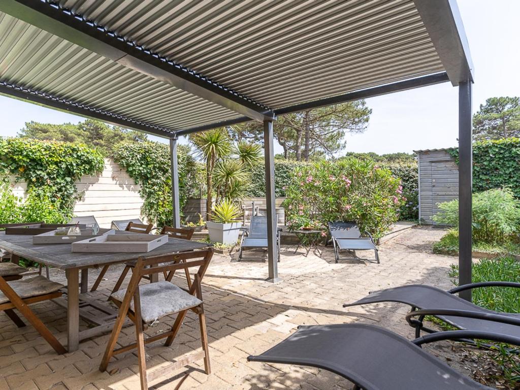 d'une terrasse avec une table et des chaises sous un auvent. dans l'établissement T3 Biscarrosse Plage, 5 pers, parking, proche océan, ménage inclus - FR-1-319-577, à Biscarrosse