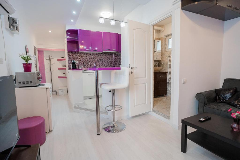 a kitchen and a living room with purple cabinets at Ultra Central White & Lila Studio in Bucharest