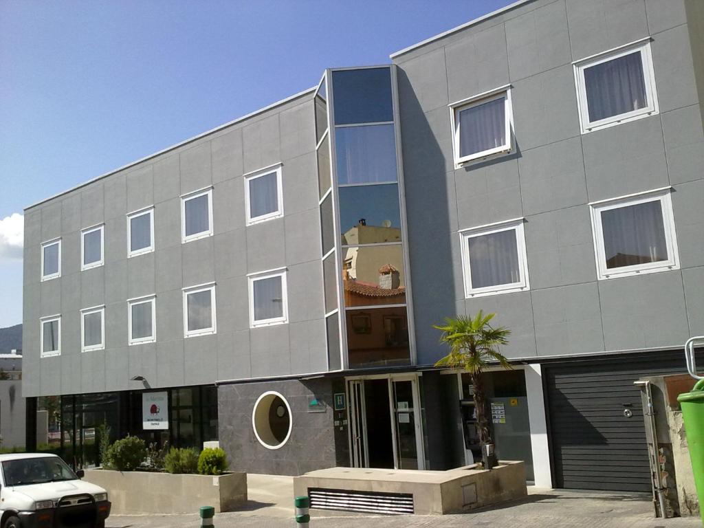 a gray building with a palm tree in front of it at Hotel Montmeló in Montmeló