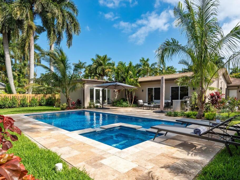 una piscina davanti a una casa con palme di Amazing Family Home in Hollywood FL a Hollywood