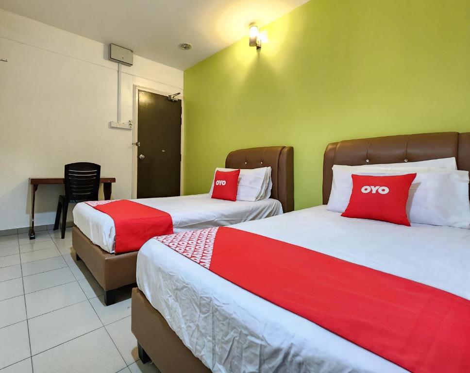 a hotel room with two beds with red and white pillows at Hotel O Ban Cheong in Kangar