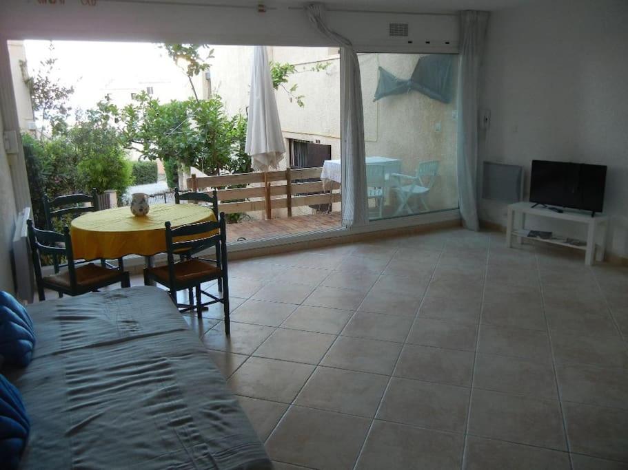 Una sala de estar con una mesa y sillas y un televisor. en Pt prixappart au calme vue mer, en Bandol