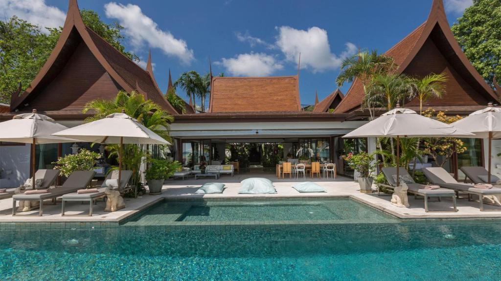 - une piscine avec des chaises et des parasols à côté d'une maison dans l'établissement Chic Baan Capo - Luxury Four Bedroom Beachfront Villa, à Bangrak Beach