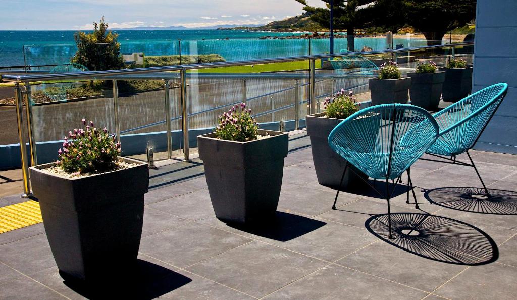 a balcony with a blue chair and potted plants at Penguin Beachfront Apartments in Penguin