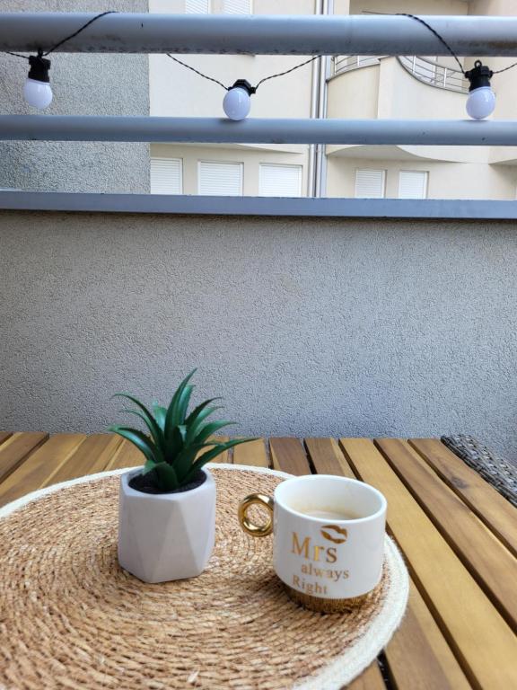 a table with a coffee cup and a plant on it at Dule Lux in Jagodina