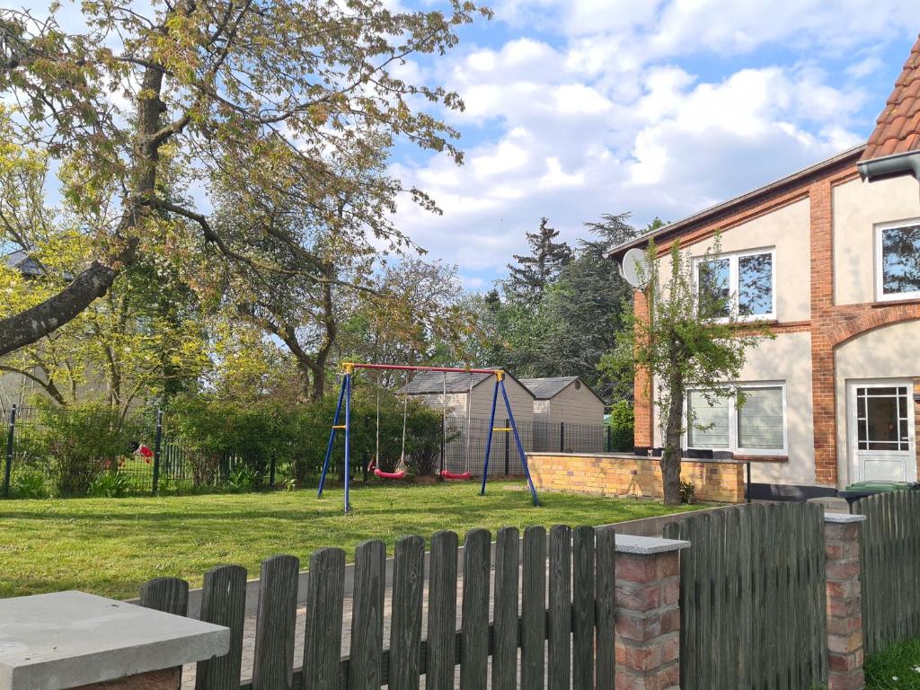 einen Hof mit einer Schaukel und einem Haus in der Unterkunft Landhaus am Bauernhof im Ostseeland in Boldenshagen