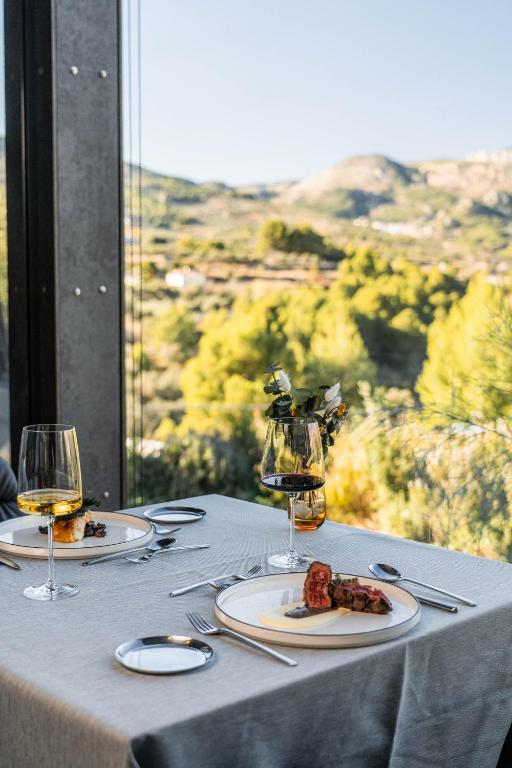 una mesa con platos de comida y copas de vino en VIVOOD Landscape Hotel & Spa - Designed for Adults, en Benimantell