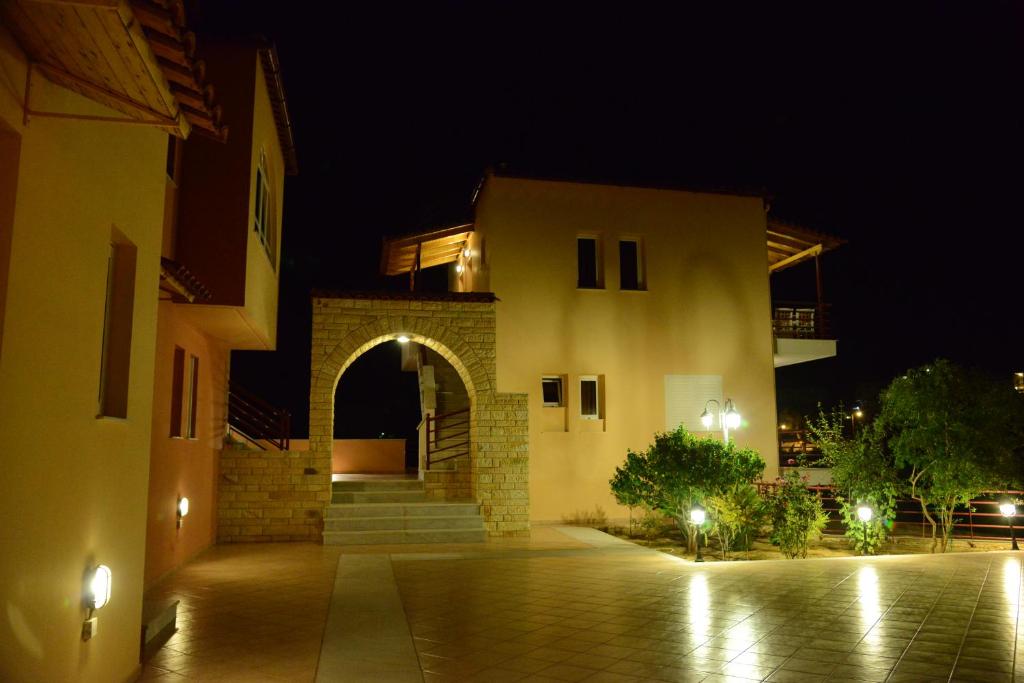 un bâtiment avec une arche devant lui la nuit dans l'établissement Maria's Filoxenia Suites, à Drepano