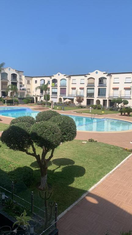 a tree in front of a building with a swimming pool at Magic House Mansouria in Mansouria