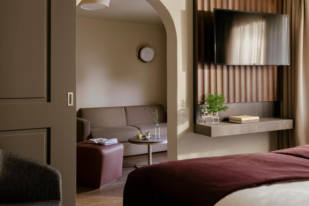a bedroom with a bed and a couch and a table at SCHLOSS Zermatt - CBD & Adaptogenic Spa and Sport Hotel in Zermatt