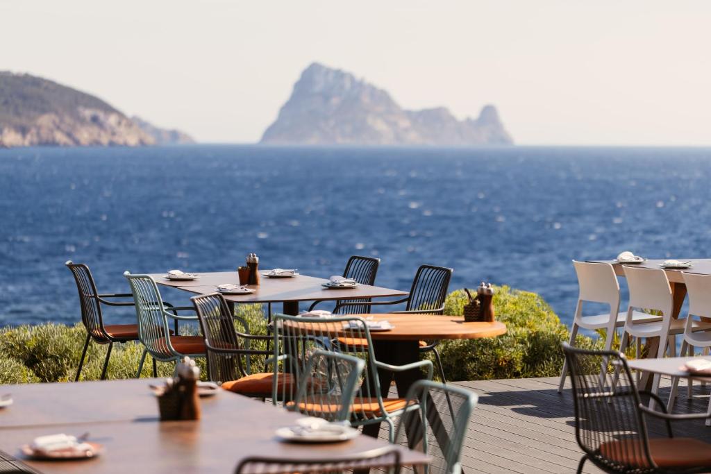 a row of tables and chairs with a view of the ocean at 7Pines Resort Ibiza, part of Destination by Hyatt in San Jose