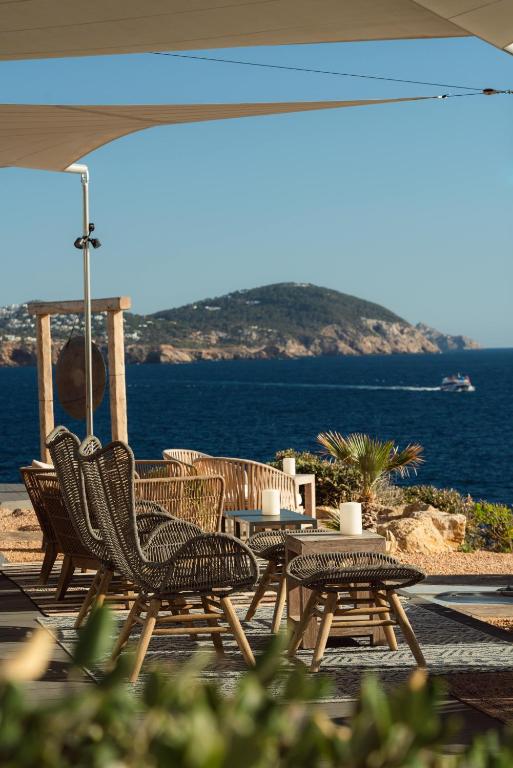 a group of chairs and tables with the ocean in the background at 7Pines Resort Ibiza, part of Destination by Hyatt in San Jose
