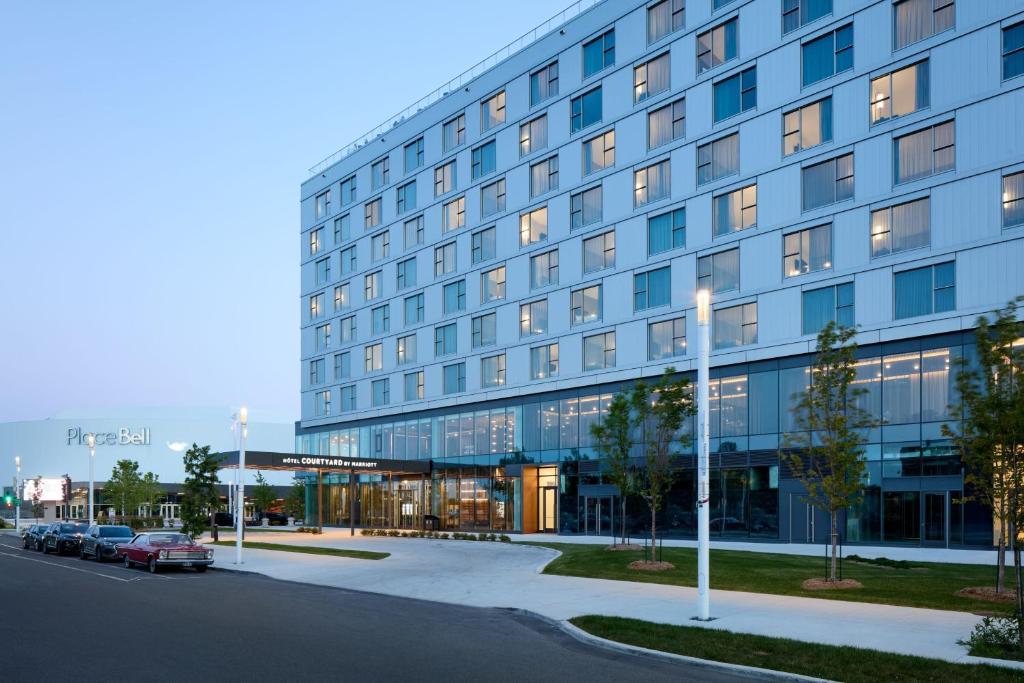 拉瓦尔Courtyard by Marriott Montreal Laval的一座大楼，前面停满了汽车