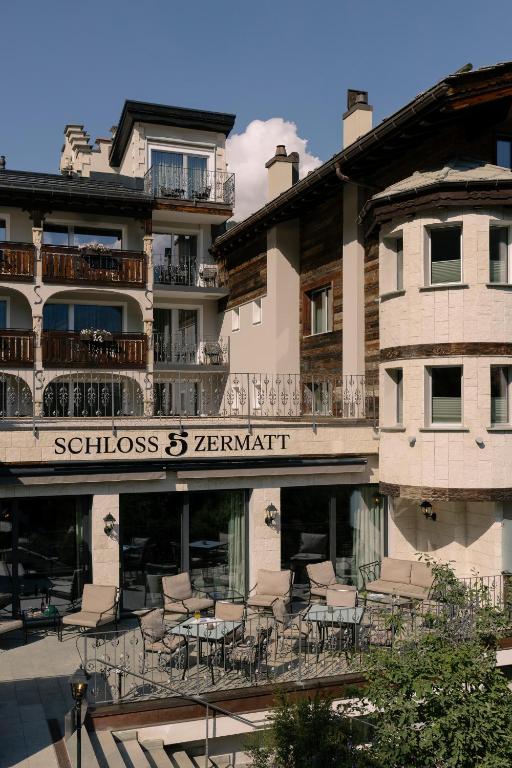 a building with chairs and tables on a balcony at SCHLOSS Zermatt - CBD & Adaptogenic Spa and Sport Hotel in Zermatt