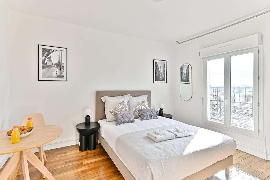 une chambre blanche avec un grand lit et une table dans l'établissement Studio confortable - Havre de Paix proche Paris, à Montreuil