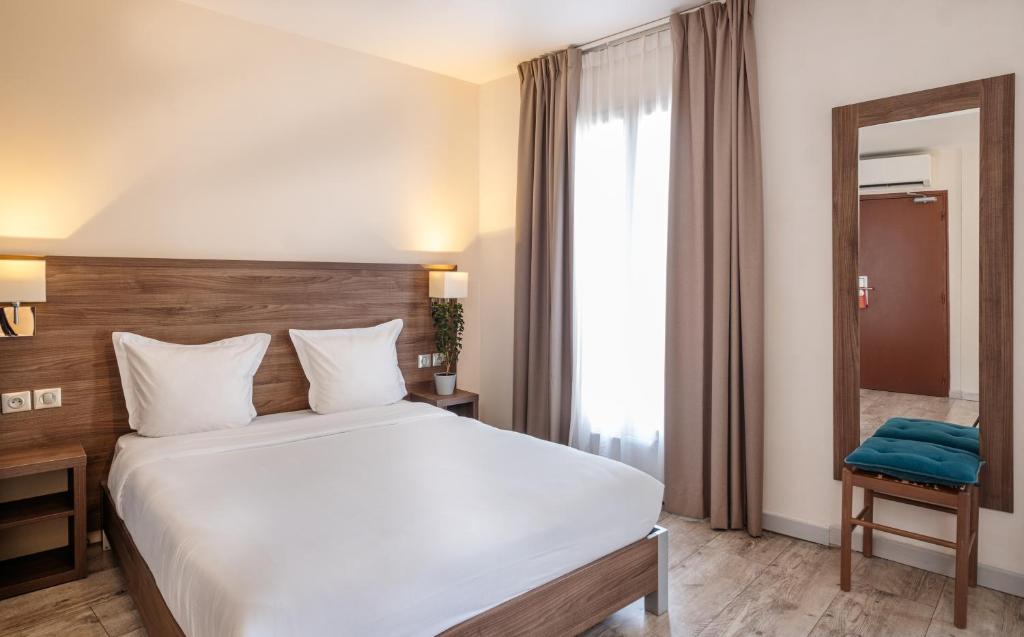 a bedroom with a large bed and a large window at Hotel la Perle Montparnasse in Paris