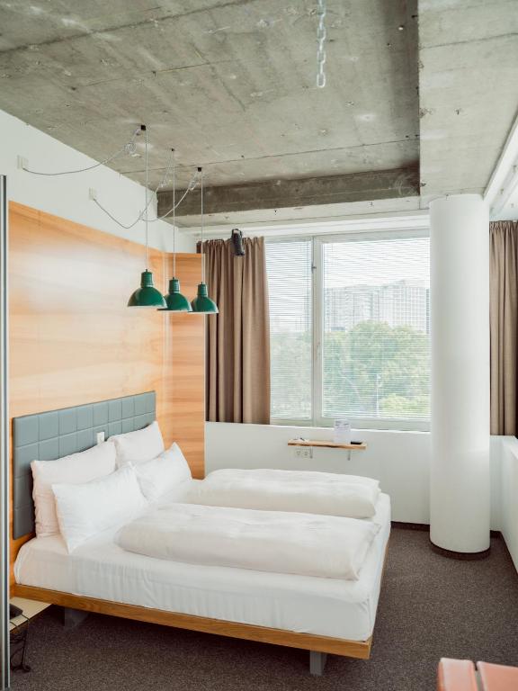 a bedroom with two beds and a large window at Hotel Daniel Vienna - Smart Lifestyle Near City Centre in Vienna