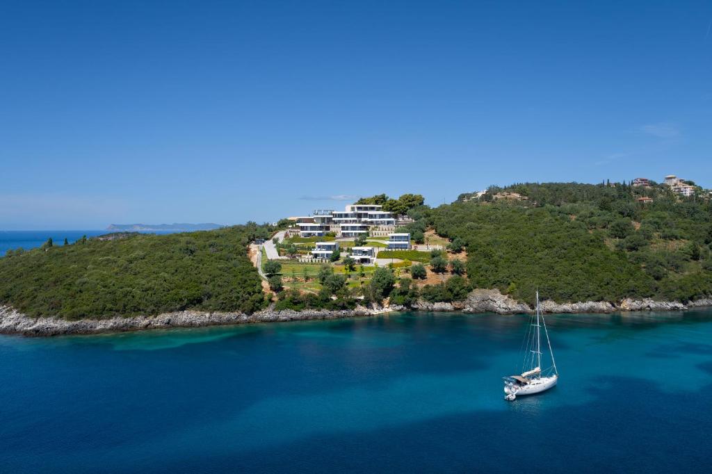a boat in the water in front of a house on an island at Zavia Resort in Syvota