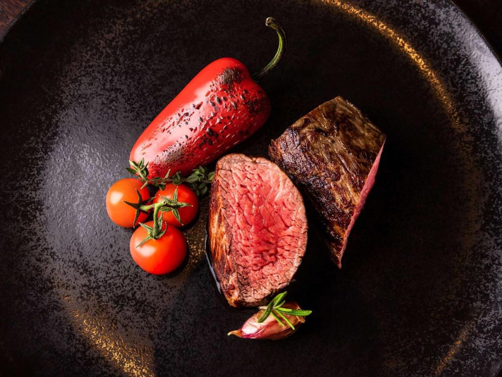 a plate with beef steak and a strawberry and tomatoes at Sofitel Luxembourg Europe in Luxembourg