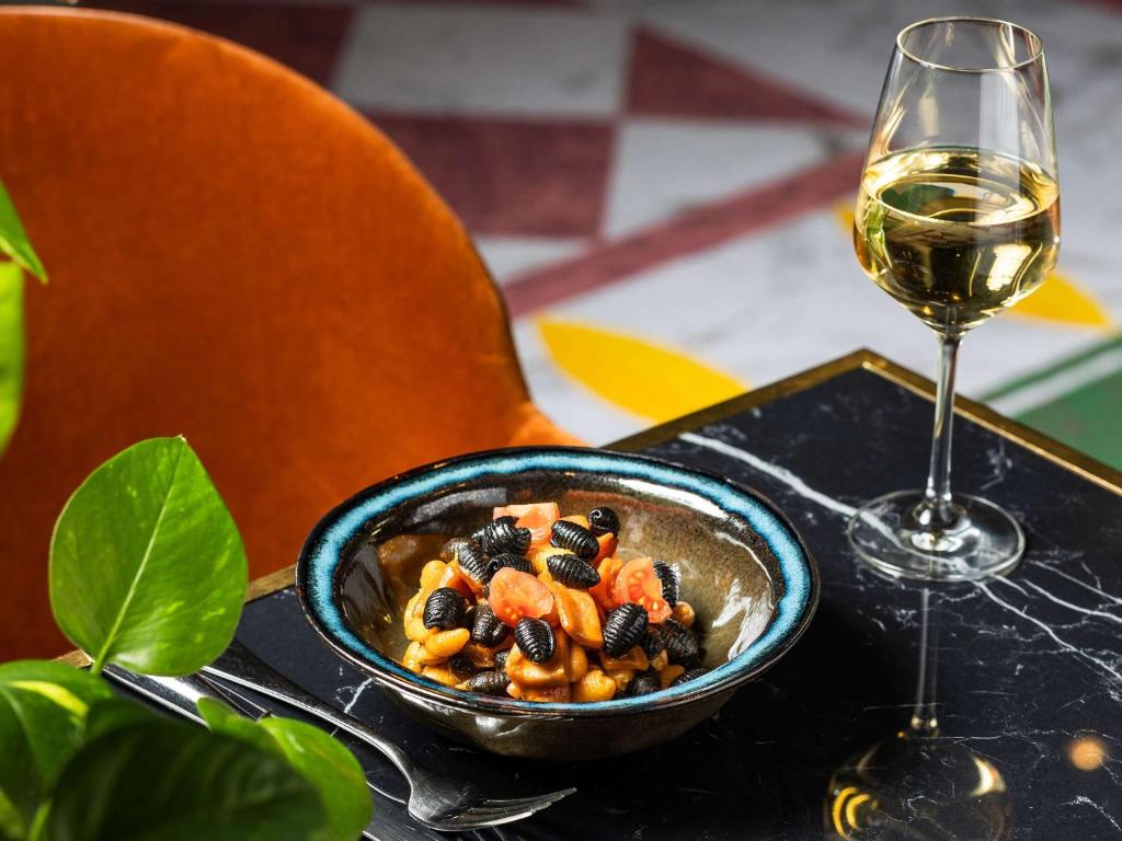 a bowl of food next to a glass of wine at Sofitel Luxembourg Europe in Luxembourg