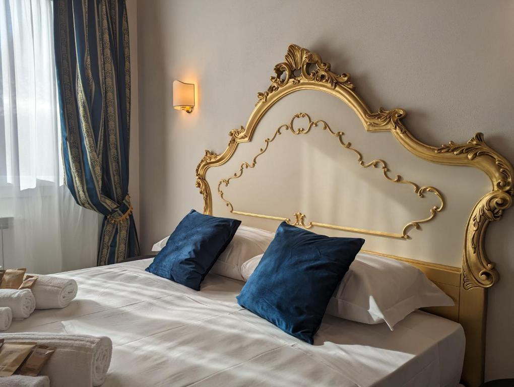 a bed with a gold frame and blue pillows on it at FloVe' Rooms Venice in Venice