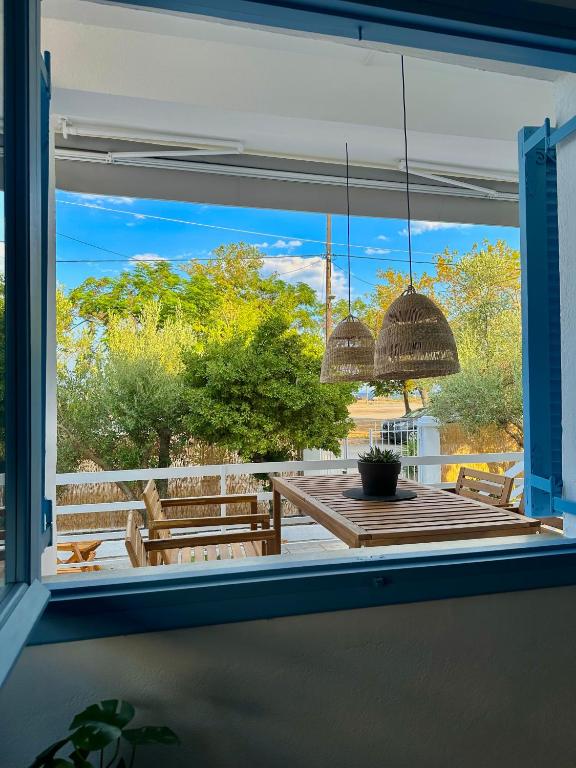 a window view of a patio with a table and benches at Assamaris Beachfront House in Asprovalta
