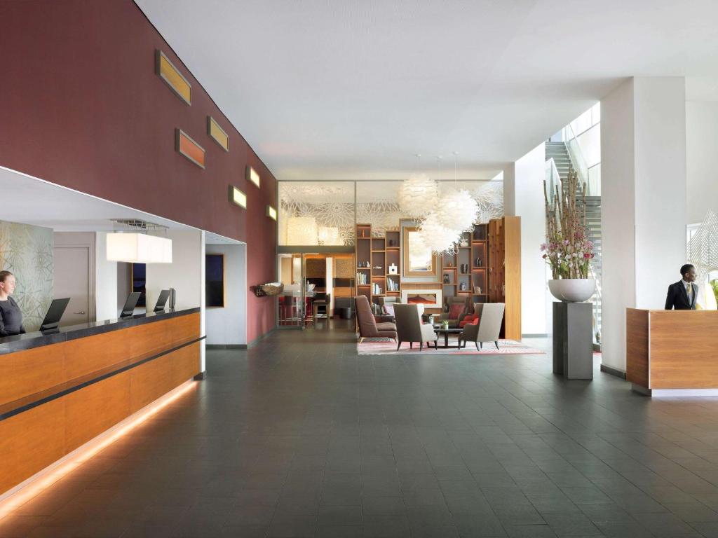 un hall avec des personnes assises à un bureau dans un bâtiment dans l'établissement Mövenpick Hotel Amsterdam City Centre, à Amsterdam