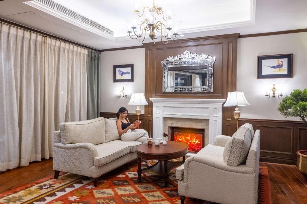a woman sitting in a living room with a fireplace at Namah Nainital, a member of Radisson Individuals Retreats in Nainital