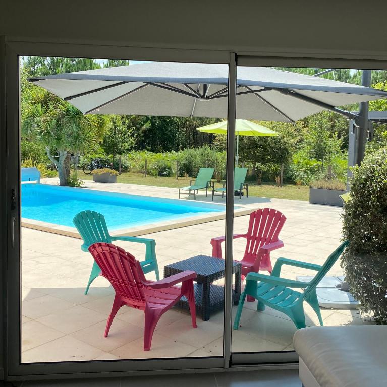 a patio with three chairs and a table with an umbrella at Villa Caplanne in Sanguinet