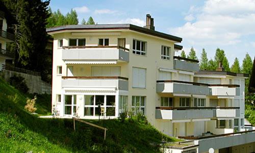 duży biały budynek na szczycie wzgórza w obiekcie Residenz Larix Apartments w Davos