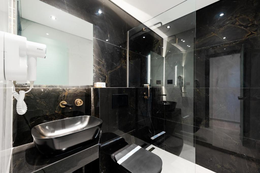 bagno nero con lavandino e specchio di Kefi Executive Villa a Chrisi Ammoudia