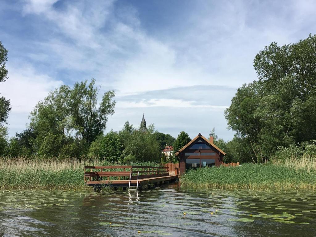 a cabin on the side of a river with a dock at Ferienhaus Haus am See in Sternberg