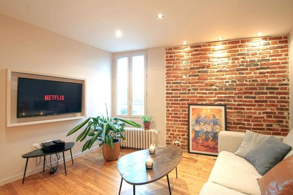 un salon avec un canapé et un mur de briques dans l'établissement Ty ar kazarn Foch - Colombier - Champ-de-Mars, à Rennes