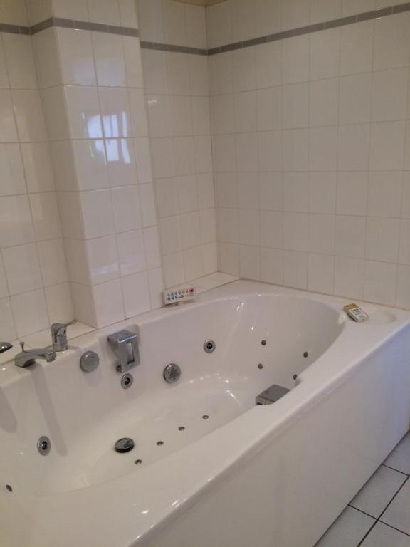 a white bath tub in a white tiled bathroom at Juniper House in Vulaines-sur-Seine