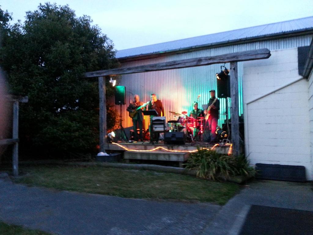 Eine Gruppe von Menschen auf einer Bühne in einer Garage in der Unterkunft Gladstone Hotel in Fairlie