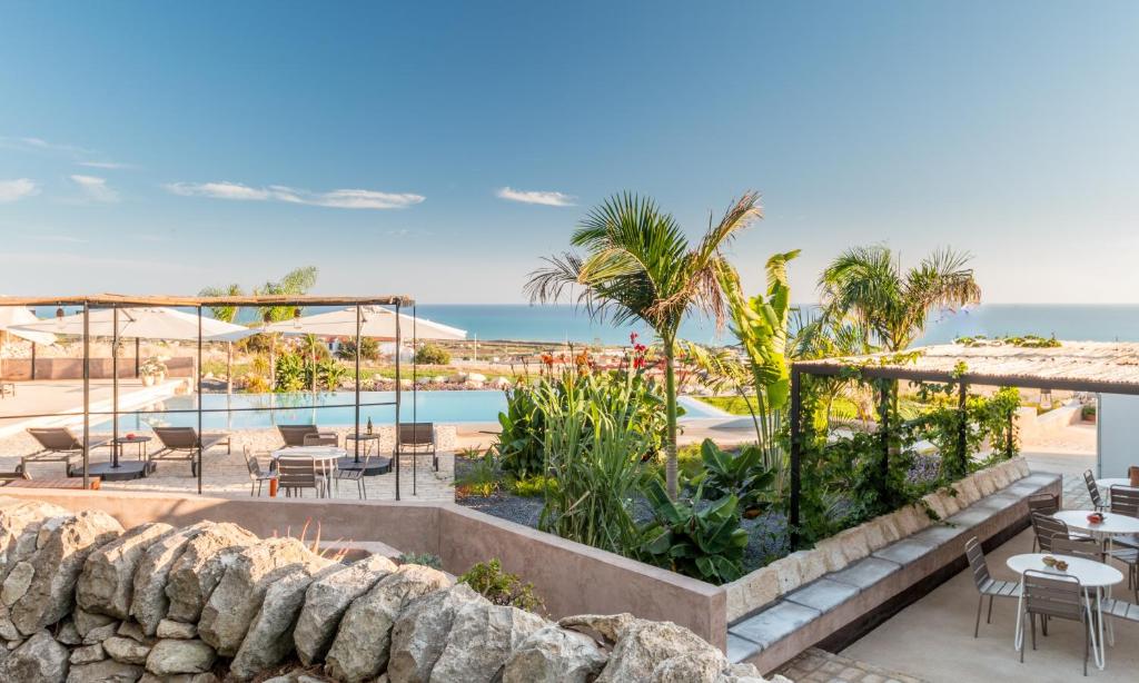 een uitzicht op een resort met tafels en stoelen en de oceaan bij Mangiabove in Marina di Ragusa