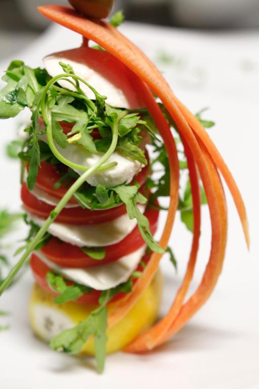 a sandwich with tomatoes and onions on a plate at Hotel Villa Margherita in Quercianella