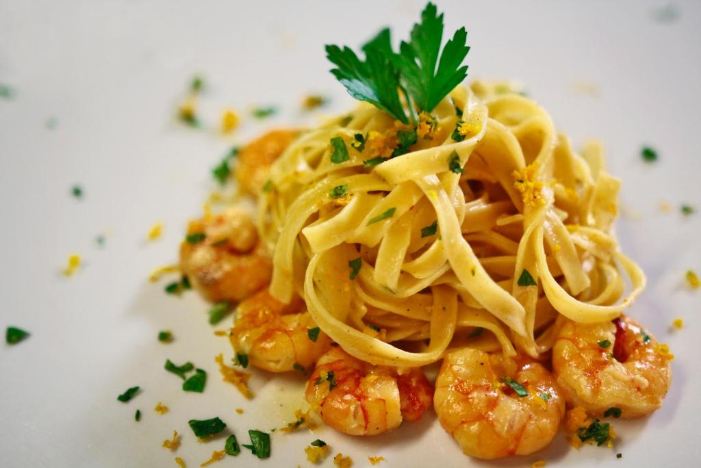 a plate of pasta with shrimp on a white plate at Hotel Villa Margherita in Quercianella