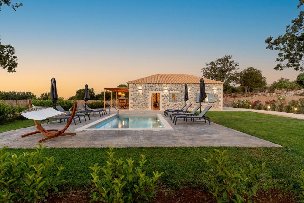 a backyard with a pool and chairs and a house at Miroy Mountain View Villa in Prinés