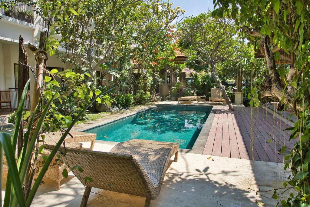 a swimming pool in a yard with a chair and trees at Bali Telaga Hati Yoga Healing And Retreat Center Hostel in Sanur