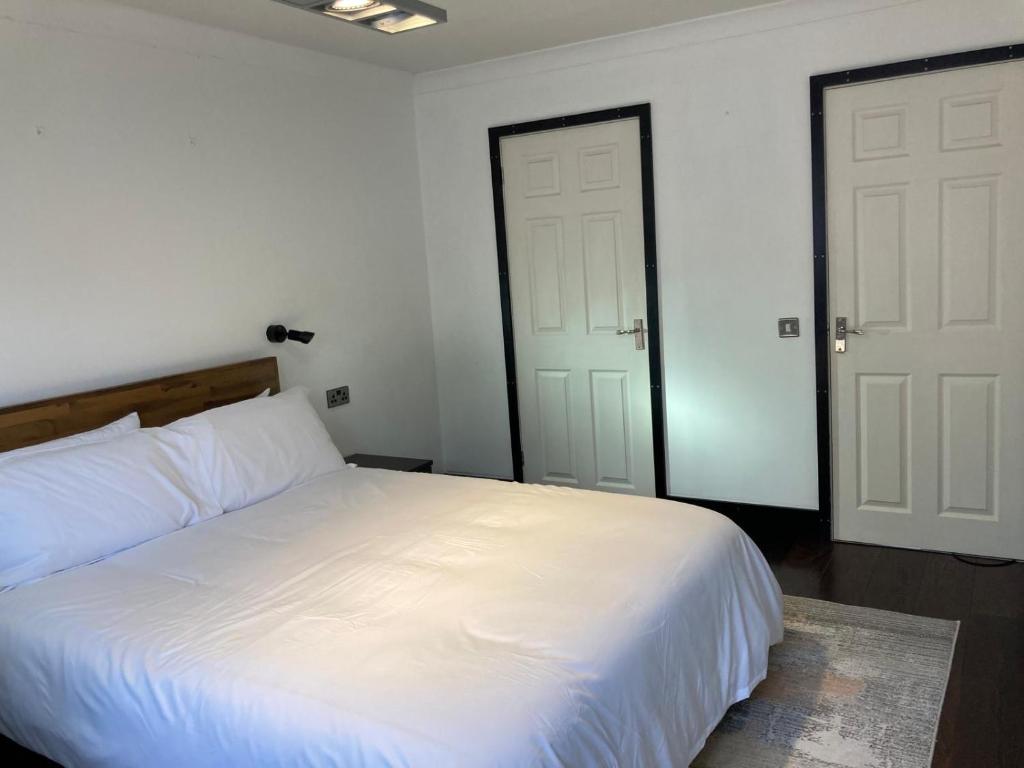 a bedroom with a white bed and two doors at 2 bed Serviced Apartment in Henley in Henley on Thames