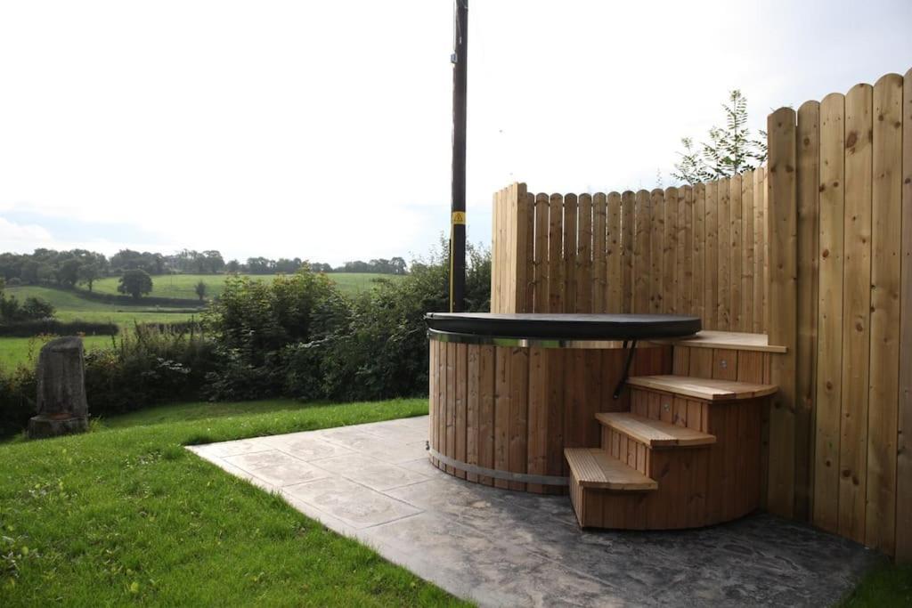 a wooden fence with a bench next to a table at Stone Gate lodge with Private Hot Tub in Boardmills